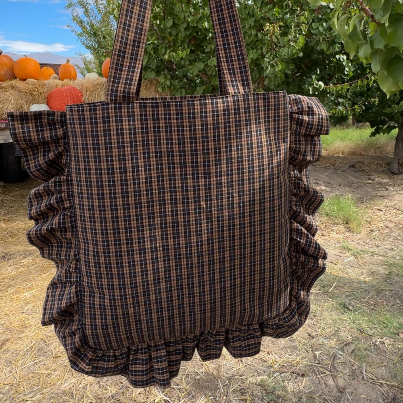 Plaid tote bag with ruffles held in front of a pumpkin patch BOLSA CON HOLANES bolsa con volante diy designerluisa imluluisa patrones