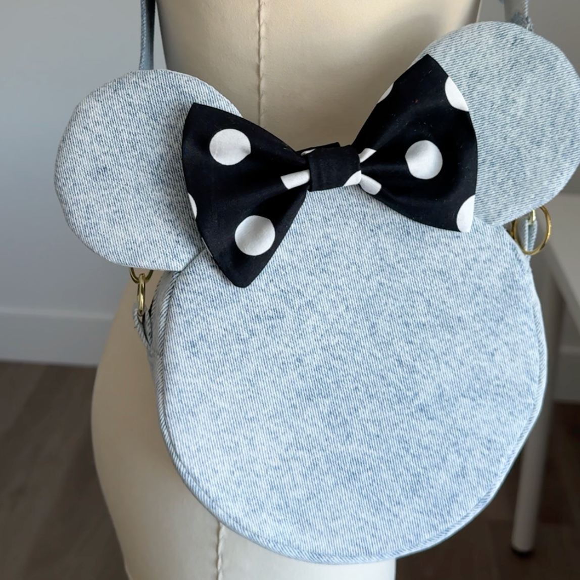 Round disney bag bag with black and white polka dot bow on a mannequin.