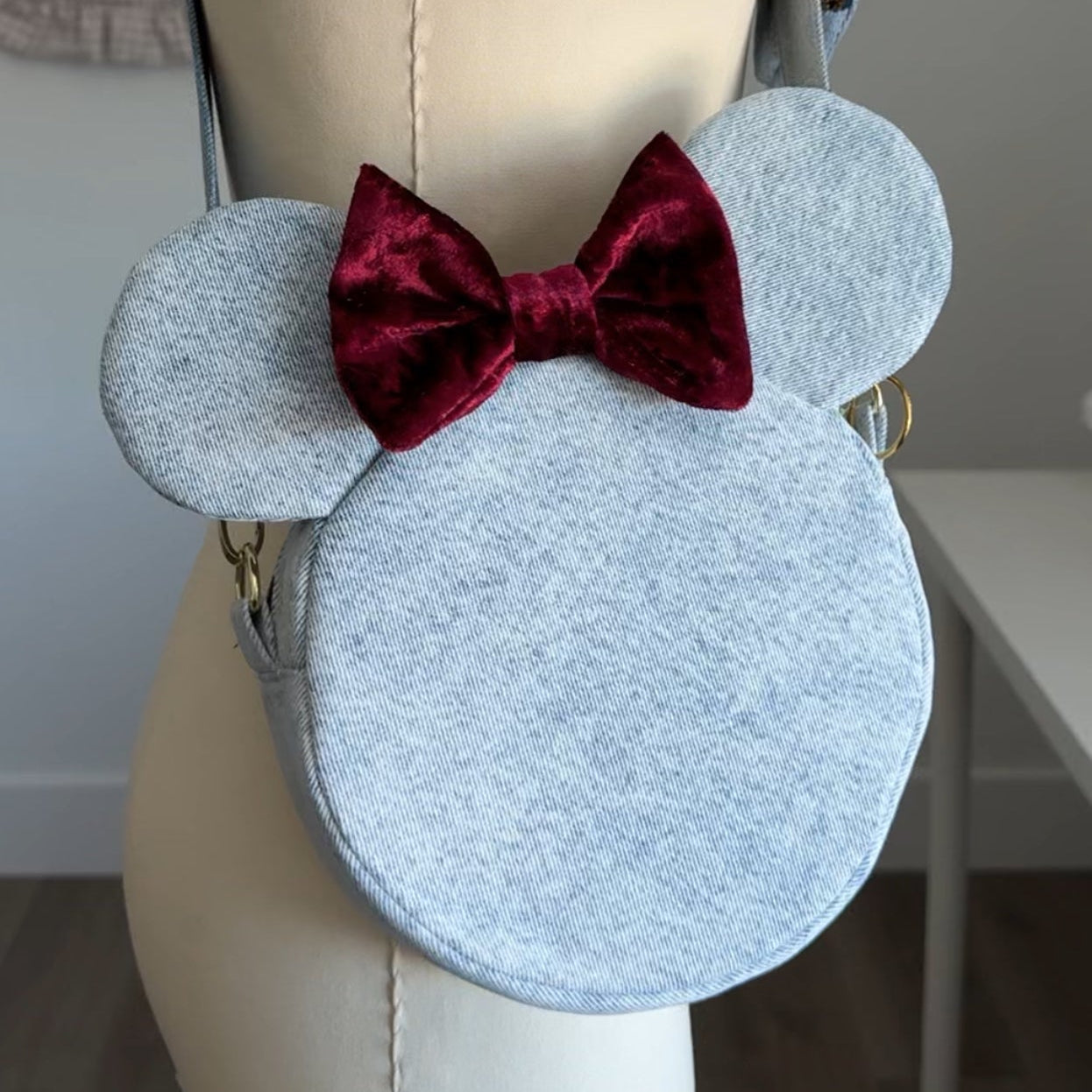Light blue bag with red bow on a mannequin against a neutral background