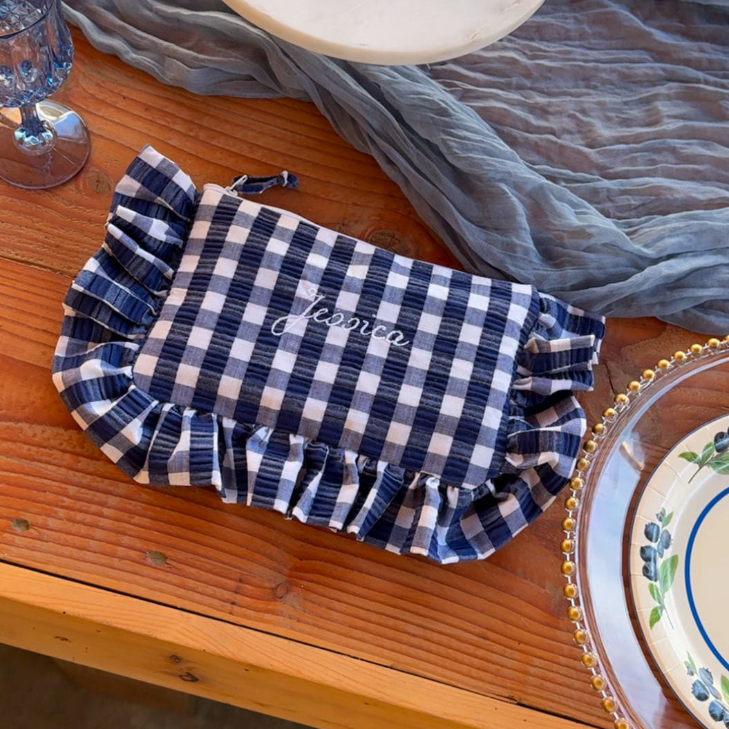 Blue and white checkered makeup puchon a wooden table with decorative plates and glasses.