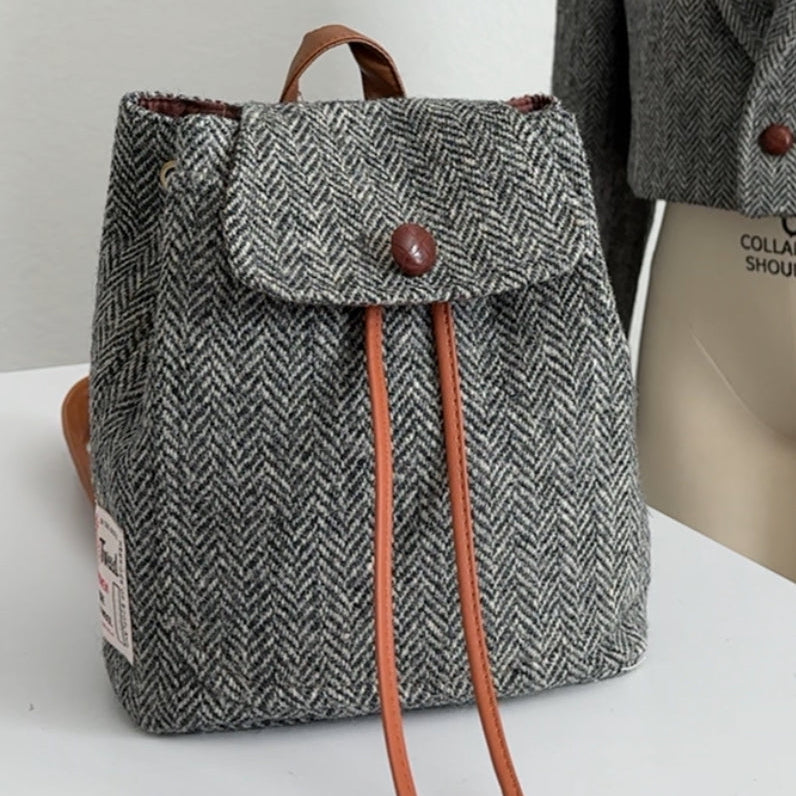 Gray herringbone backpack with brown drawstring on a white surface twwed blazer upcycled into a backpack