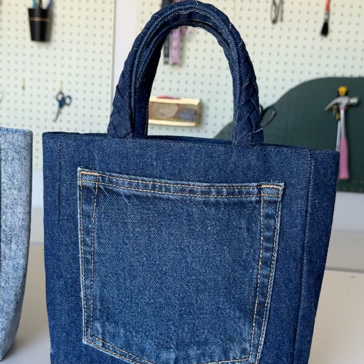 Blue denim tote bag with a pocket on a white surface