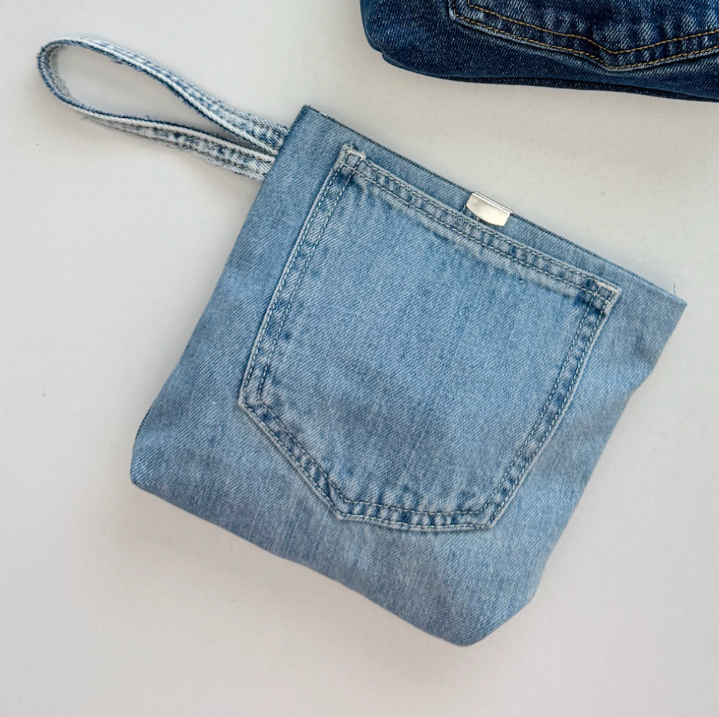 Blue denim pouch with a handle on a light gray background