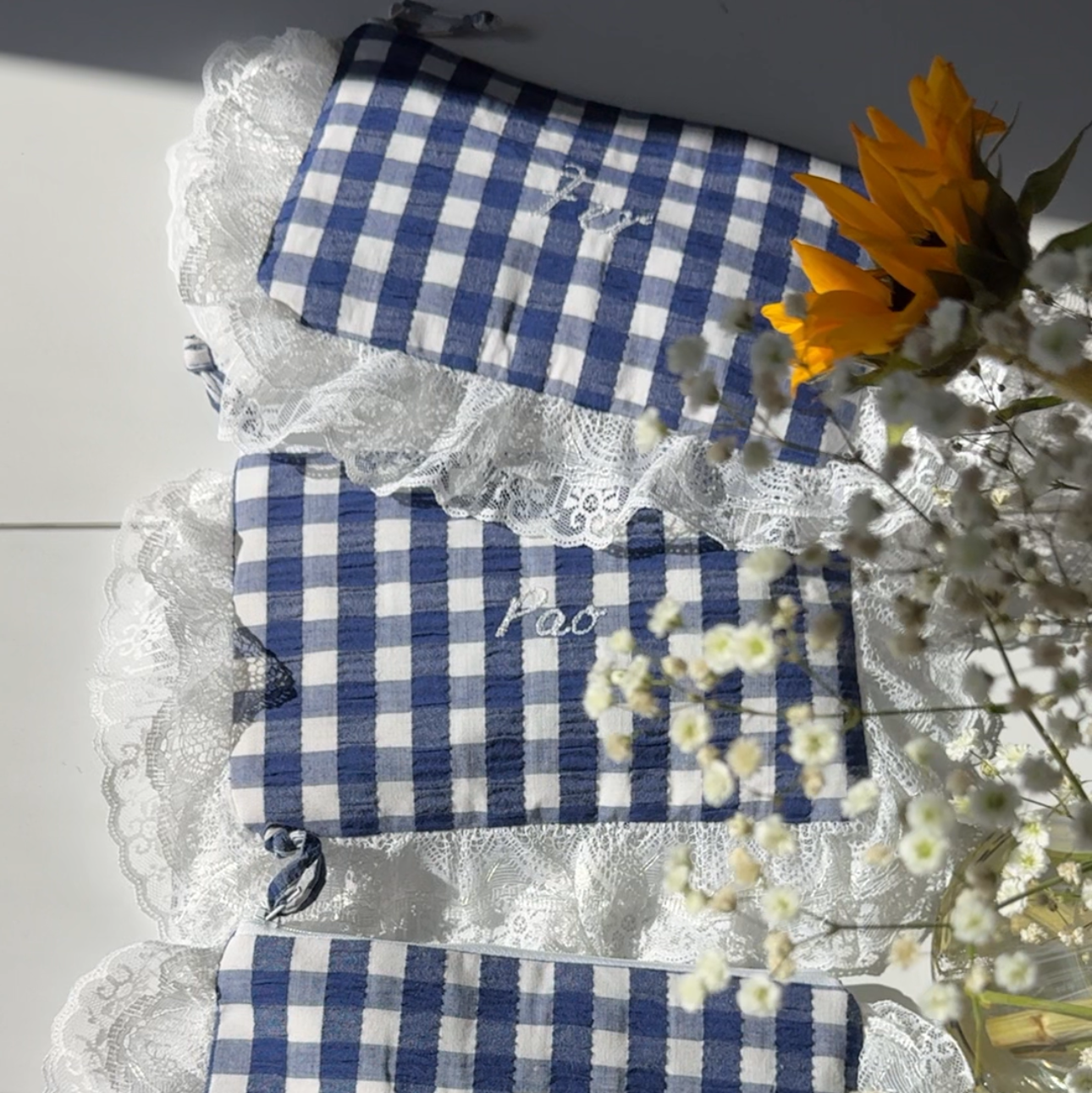 Set of blue and white checkered pouches with lace trim on a light background